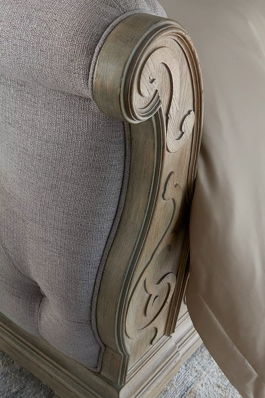 Closeup of the footboard of a Bridgeport bed showing the scroll carving in the wood in a room scene